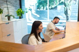 Dupla de recepcionistas trabalhando em balcão de atendimento