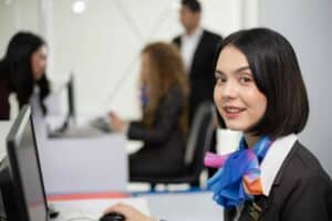 Recepcionista sorrindo sentada e olhando para a câmera