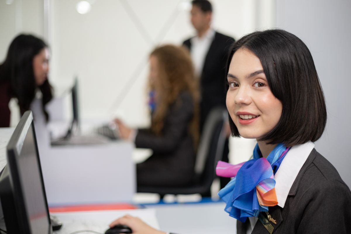 Recepcionista sorrindo sentada e olhando para a câmera